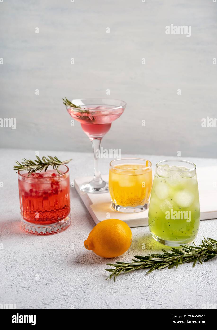 Quattro cocktail estivi colorati in bicchieri su un tavolo bianco. Assortimento di bevande fresche estive. Cocktail sangria rosa e rossa, o Foto Stock