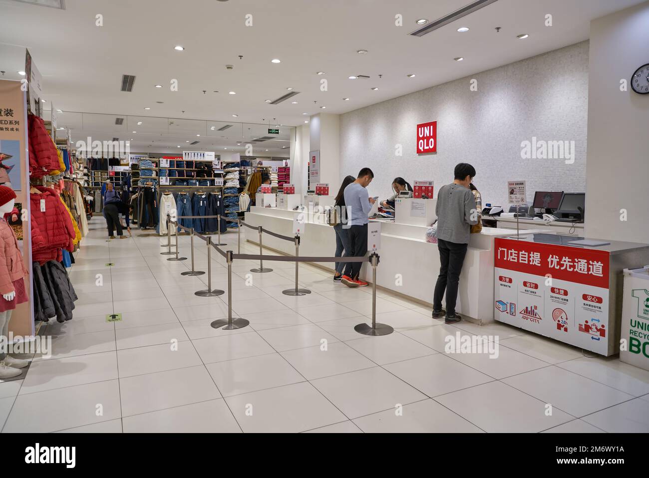 SHENZHEN, CINA - CIRCA NOVEMBRE 2019: Le persone pagano al banco di cassa nel negozio Uniqlo. Uniqlo è un designer, produttore e rivenditore di abbigliamento casual giapponese. Foto Stock