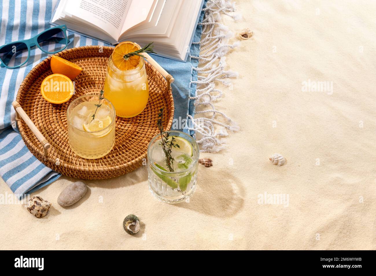 Drink estivi esotici su un vassoio di vimini sulla spiaggia con sabbia bianca. Vacanza estiva al mare e concetto di viaggio. Bevande estive esotiche. Foto Stock