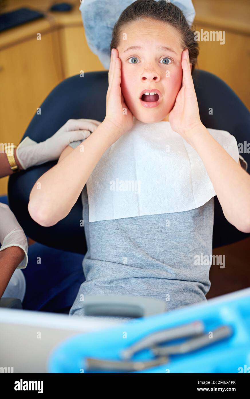 Quante cavità. una giovane ragazza che guarda terrorizzata mentre si siede in una sedia dentista. Foto Stock