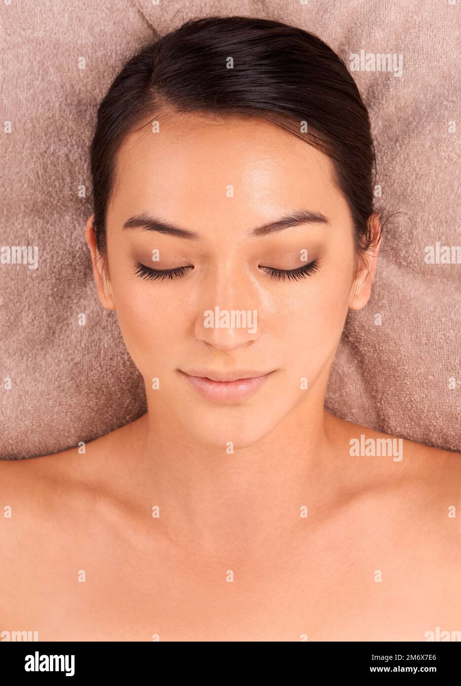 Lasciare che le cure si allontanino. Una bella giovane donna sdraiata su un letto in una day spa con gli occhi chiusi. Foto Stock