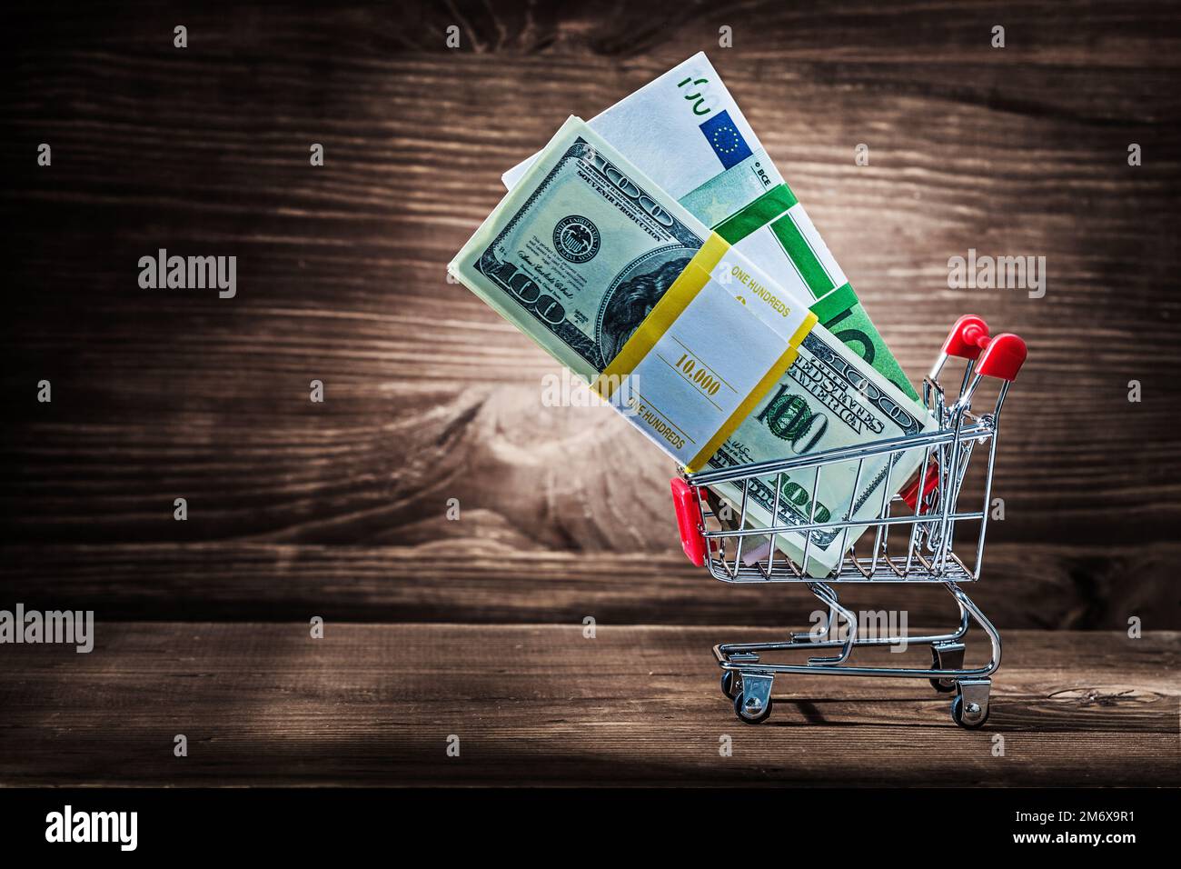 pacchetti di dollari e euro in carrello di acquisto su legno d'annata Foto Stock