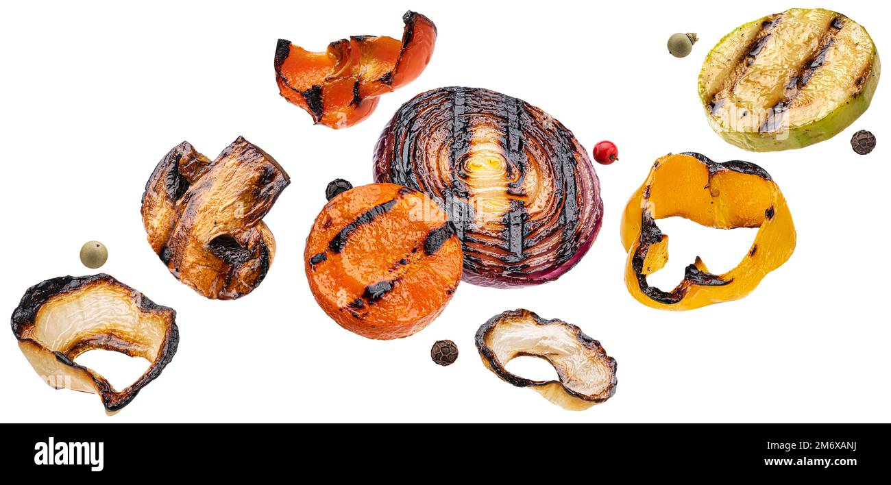 Fette di verdure grigliate che cadono isolate su sfondo bianco Foto Stock