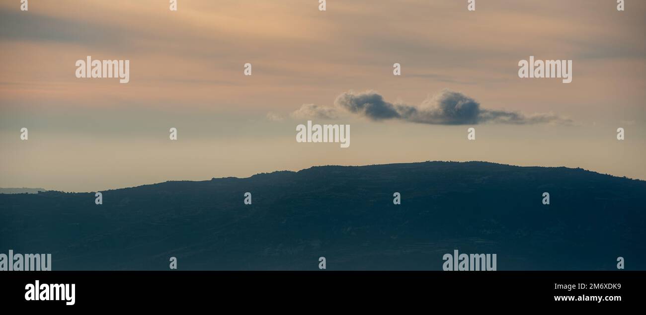 Silhouette di cime montane con nebbia e nuvole drammatiche. Tramonto colorato. Foto Stock
