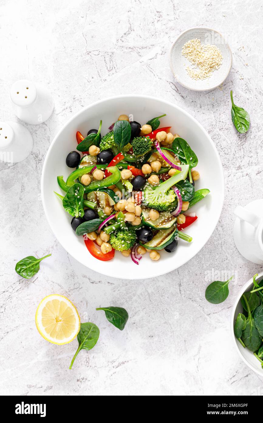 Insalata di verdure vegane di ceci e spinaci con broccoli, pepe dolce, olive e zucchine grigliate. Dieta mediterranea, cibo sano. Vista dall'alto Foto Stock