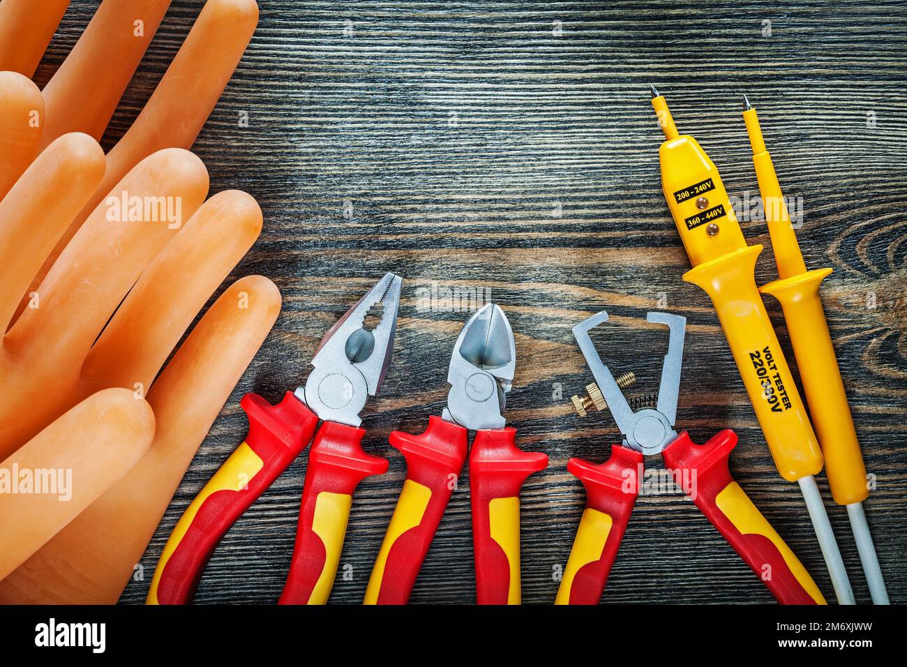 Guanti dielettrici tester elettrico spelafili isolati tronchesi pinze su legno. Foto Stock