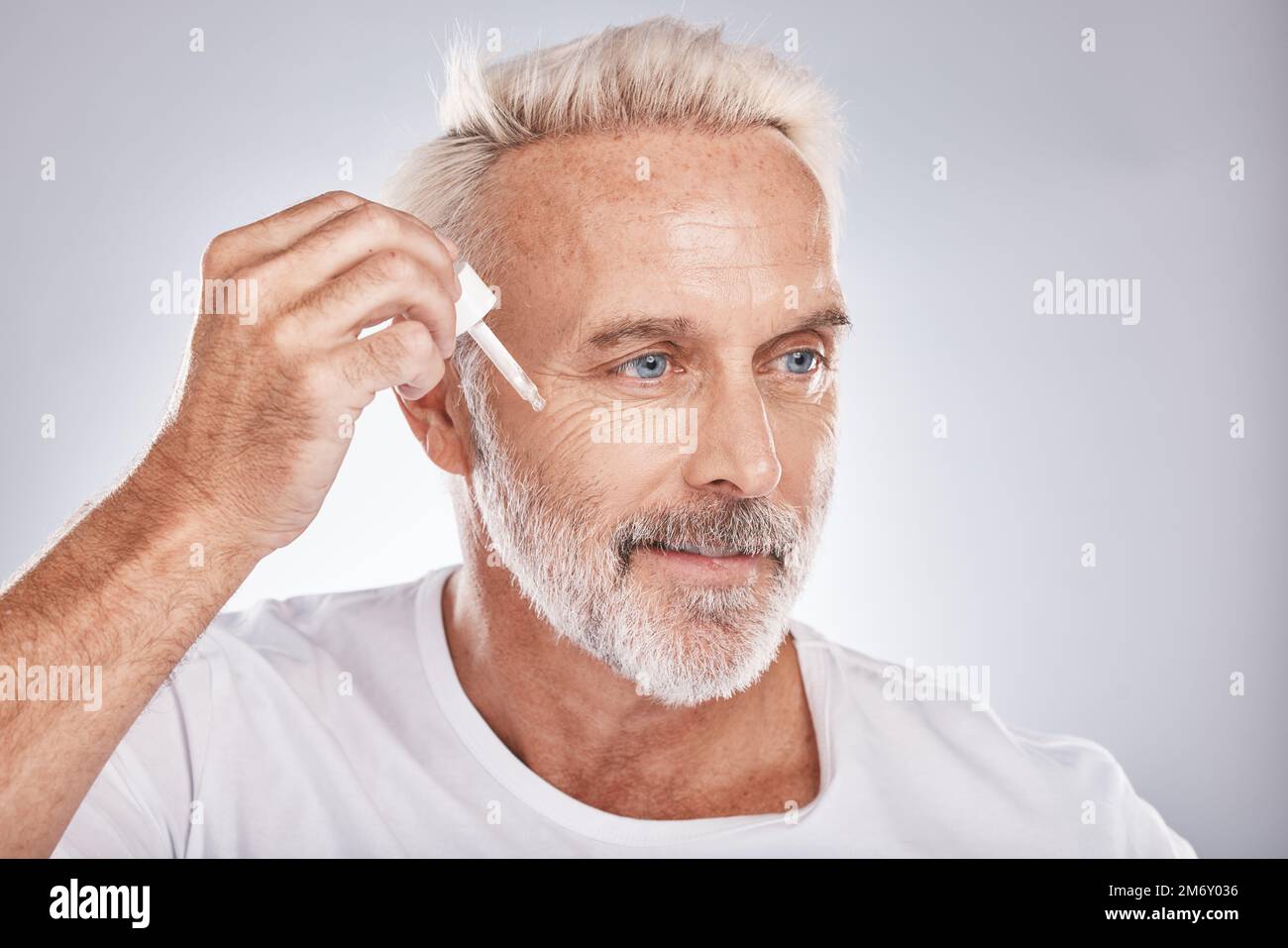 Uomo anziano, olio anti invecchiamento e benessere per la pelle del viso,  trattamenti cosmetici di bellezza e prodotti dermatologici su sfondo bianco  studio. Lusso naturale Foto stock - Alamy