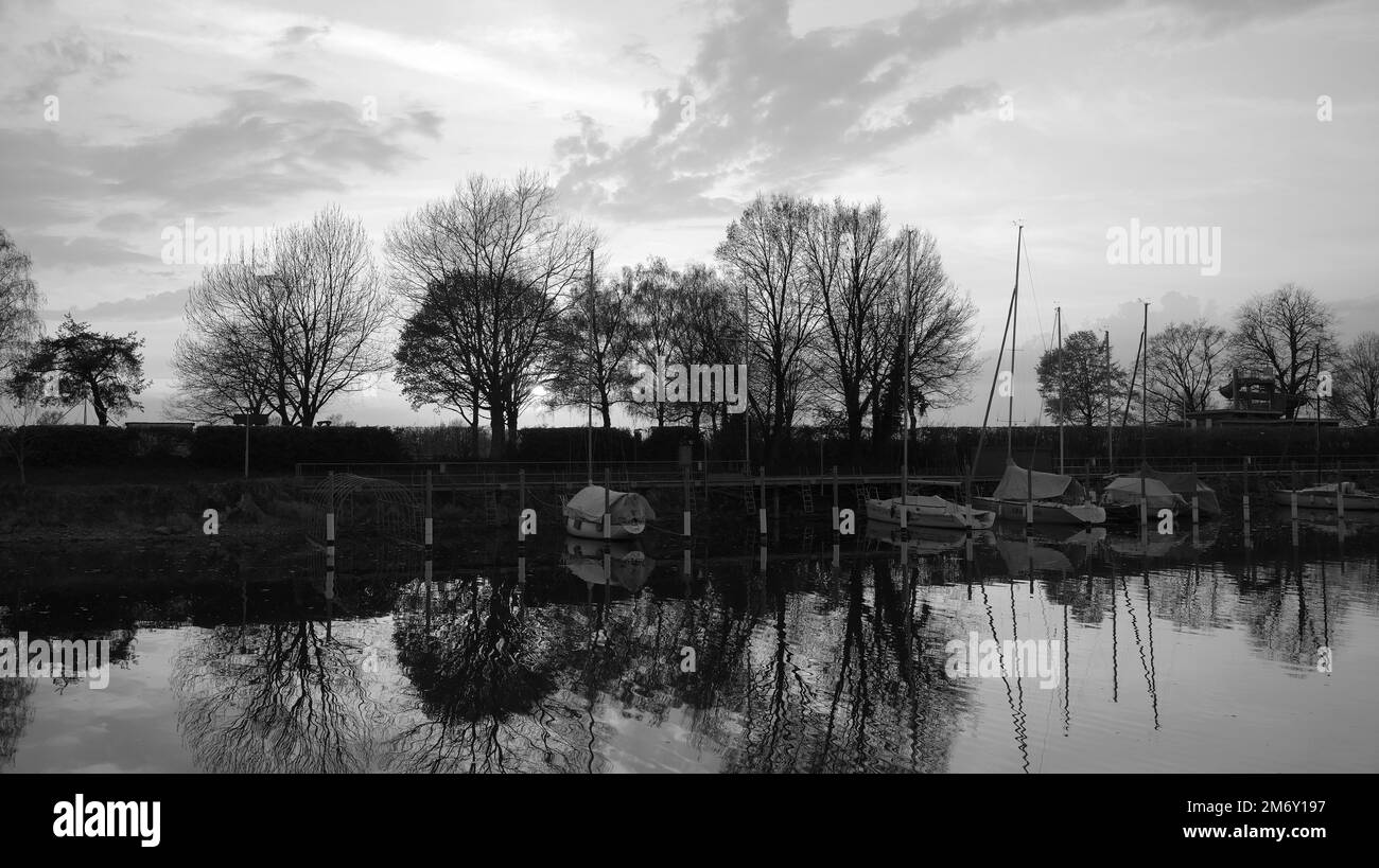 Riflessione di alberi in acqua al tramonto al piccolo porto sul lago di Costanza in Hard vicino a Bregenz in Austria con scivolo dalla piscina in background i Foto Stock