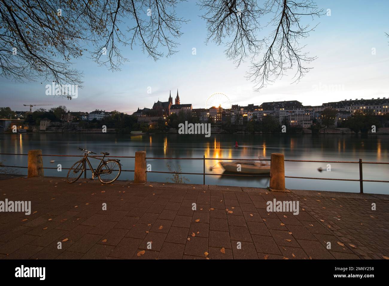 basilea svizzera, la passeggiata sul reno di sera. Sullo sfondo la cattedrale e la ruota panoramica della fiera autunnale. Foto Stock