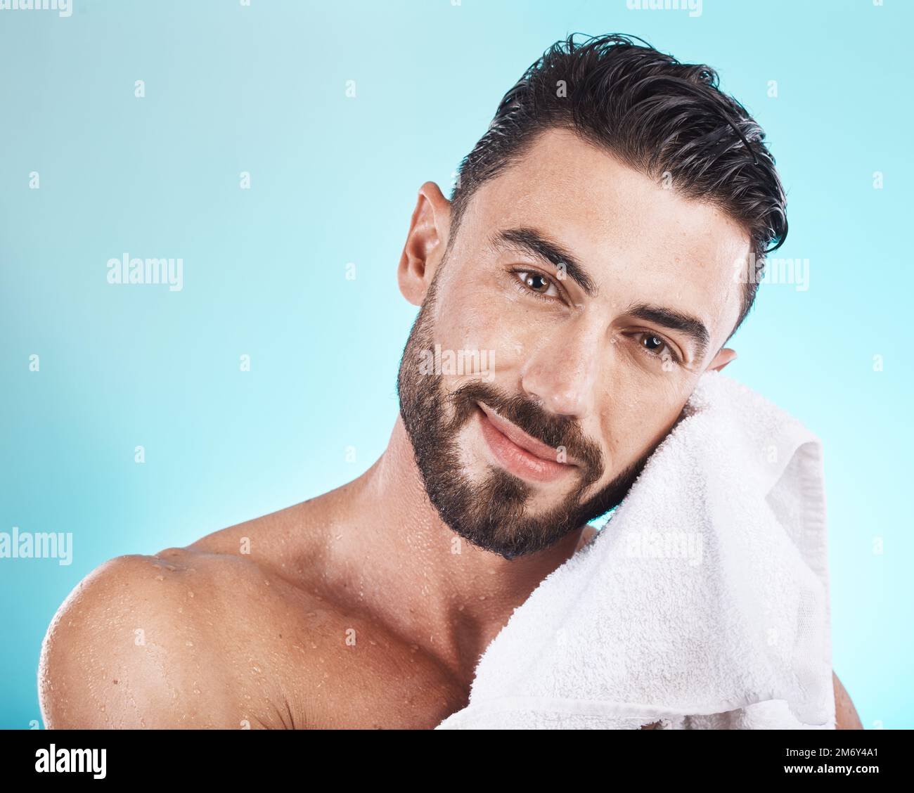 Uomo viso, asciugamano e cura della pelle quando bagnato dopo una doccia, viso o bagno per la cura della pelle, igiene e dermatologia su blu. Ritratto di felice modello maschile in Foto Stock