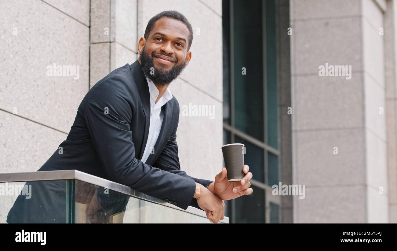 Sorridente rilassato African American società dipendente CEO ufficio manager imprenditore uomo d'affari uomo etnico ragazzo in piedi sul balcone con Foto Stock