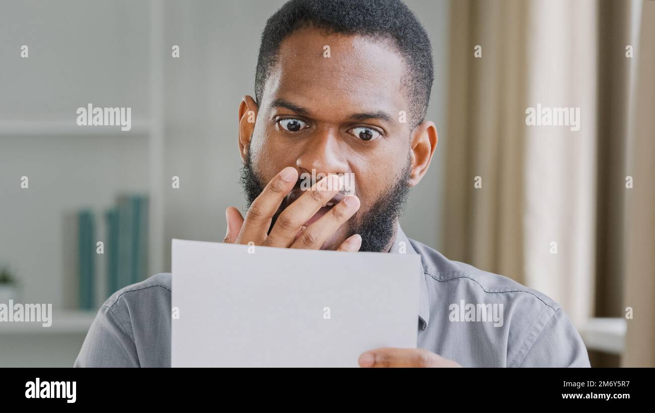 Infelice afro americano scioccato sottolineato uomo del tipo bearded in ufficio leggendo la lettera difettosa di notizie con la sensibilità di rifiuto di prestito di accreditamento della banca sollecitata circa Foto Stock