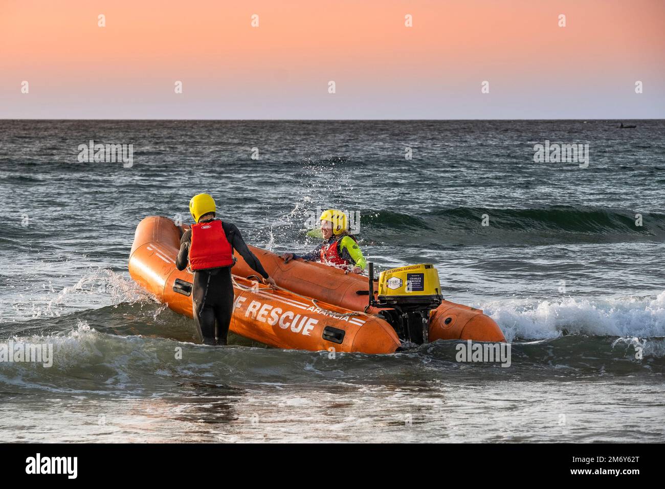 I membri del Newquay Surf Life Saving Club lanciano un'imbarcazione di salvataggio costiera di classe Arancia per una sessione di allenamento al Fistral di Newquay in Cornovaglia in t Foto Stock