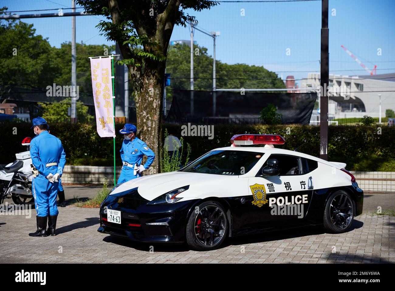 Uomini di polizia giapponesi in piedi accanto alla macchina di polizia; Giappone Foto Stock