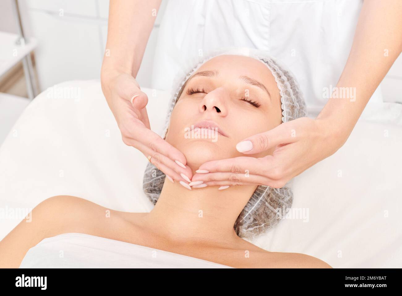Cosmetologo massaggi donna viso pelle per ringiovanimento, anti  invecchiamento cura della pelle procedura cosmetica in salone di bellezza  spa. Massaggio viso estetista Foto stock - Alamy