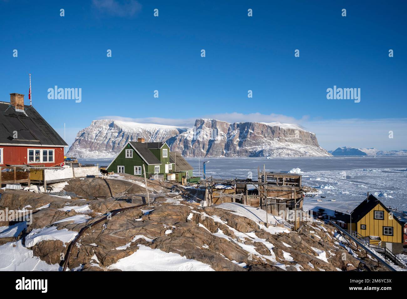 Case colorate aggrappate al lato della montagna sull'isola di Uummannaq, Groenlandia occidentale. Foto Stock