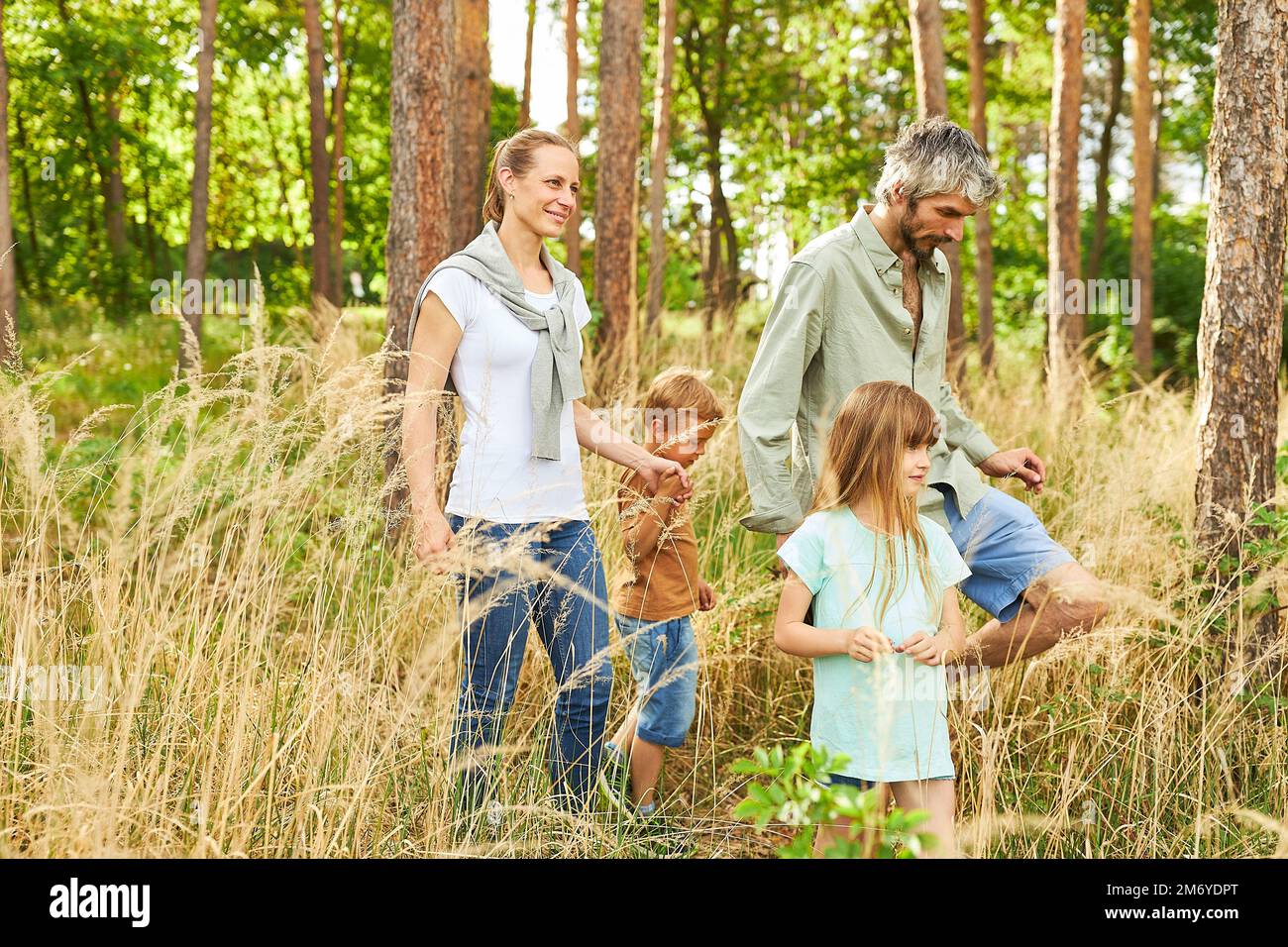 Genitori e bambini esplorano insieme nella foresta mentre camminano durante le vacanze estive Foto Stock