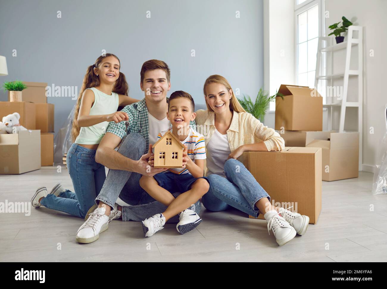 Ritratto di felice giovane famiglia caucasica di quattro nel loro nuovo appartamento luminoso. Foto Stock