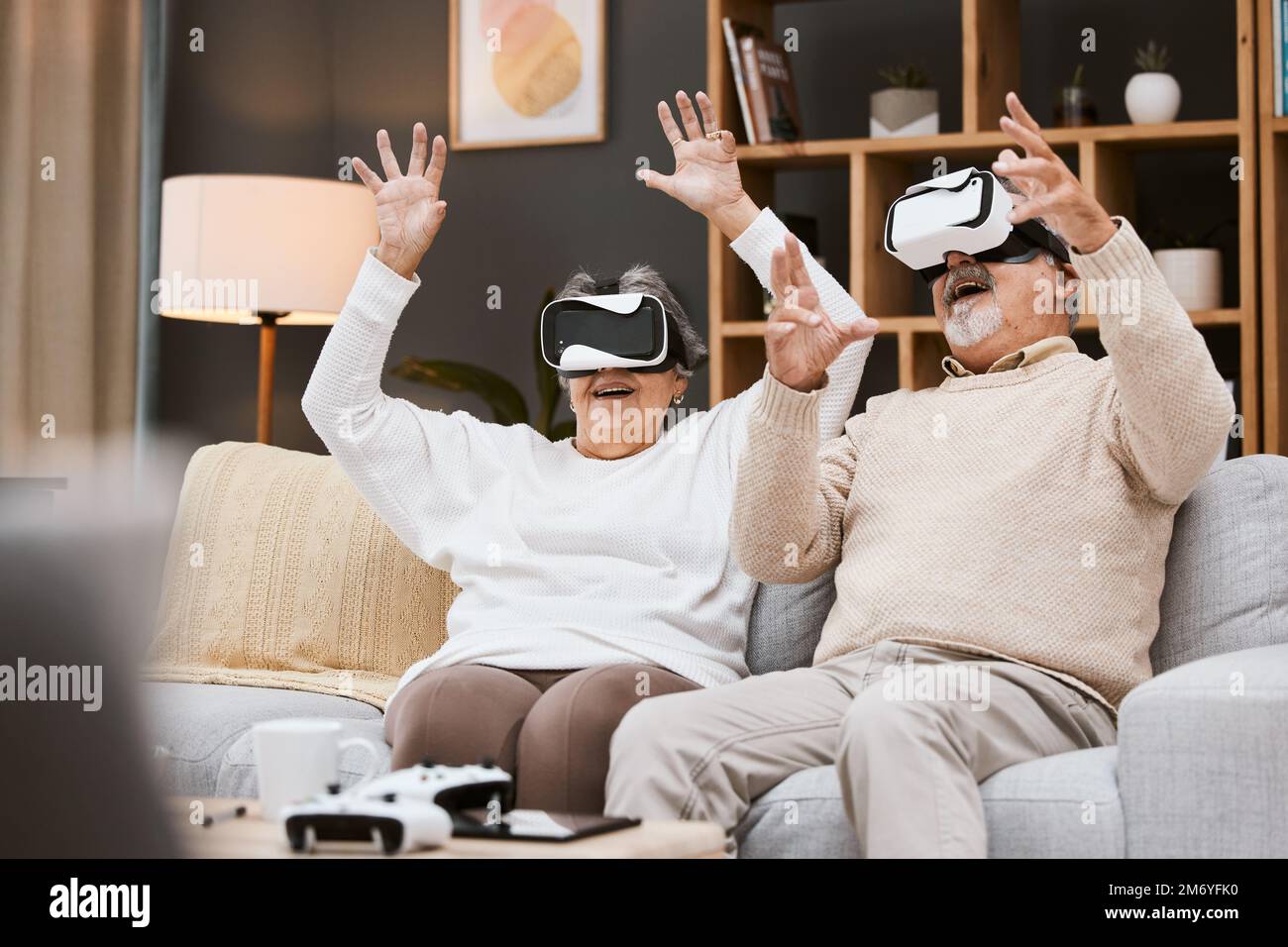 Gaming, realtà virtuale e coppia senior con visore giocano a videogame online con realtà virtuale, tecnologia e sorriso. Futuro, donna anziana e uomo felice in casa Foto Stock