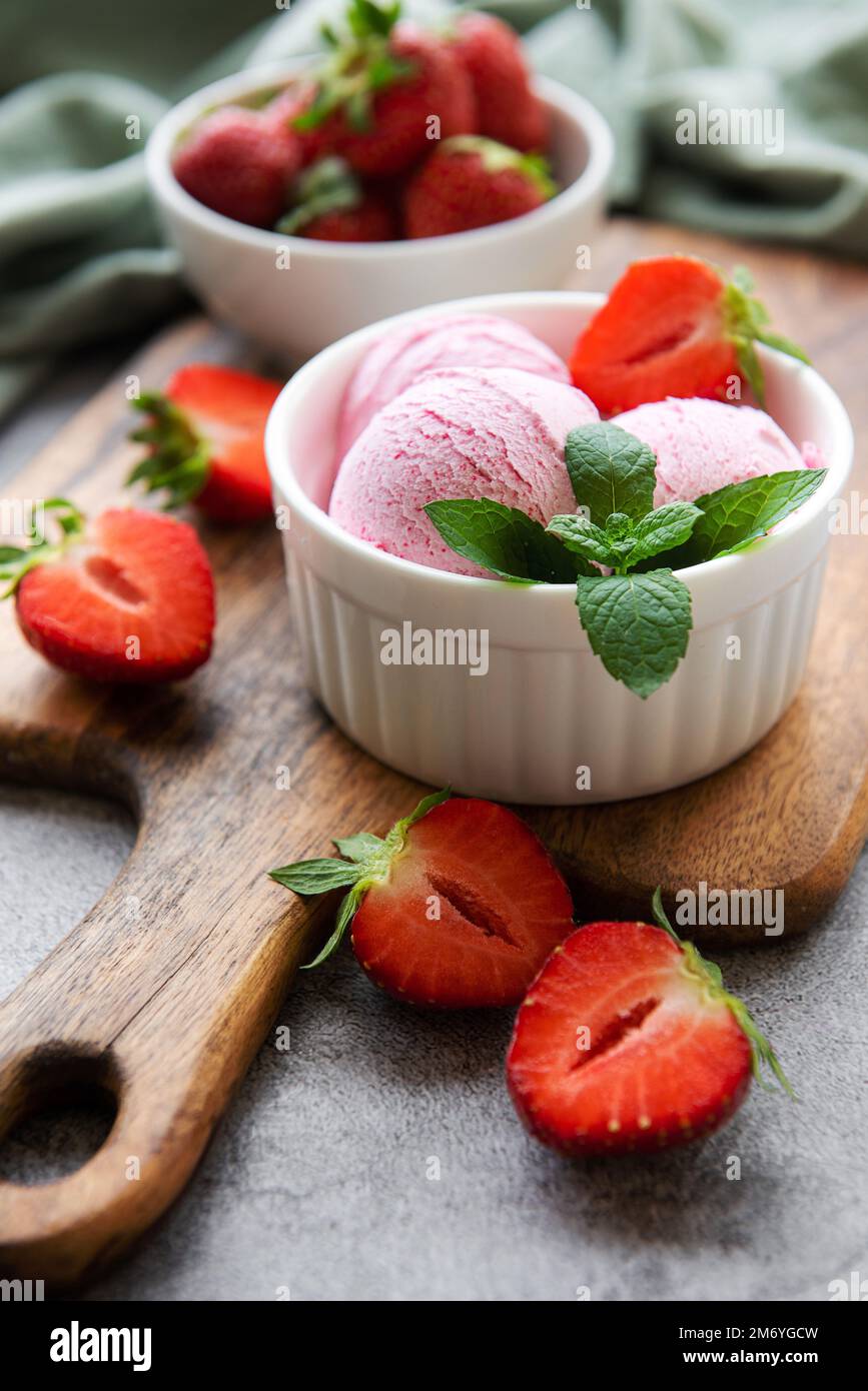 Gelato alla fragola fatto in casa con fragole fresche. Dolce bacche dessert estate. Sfondo concreto Foto Stock