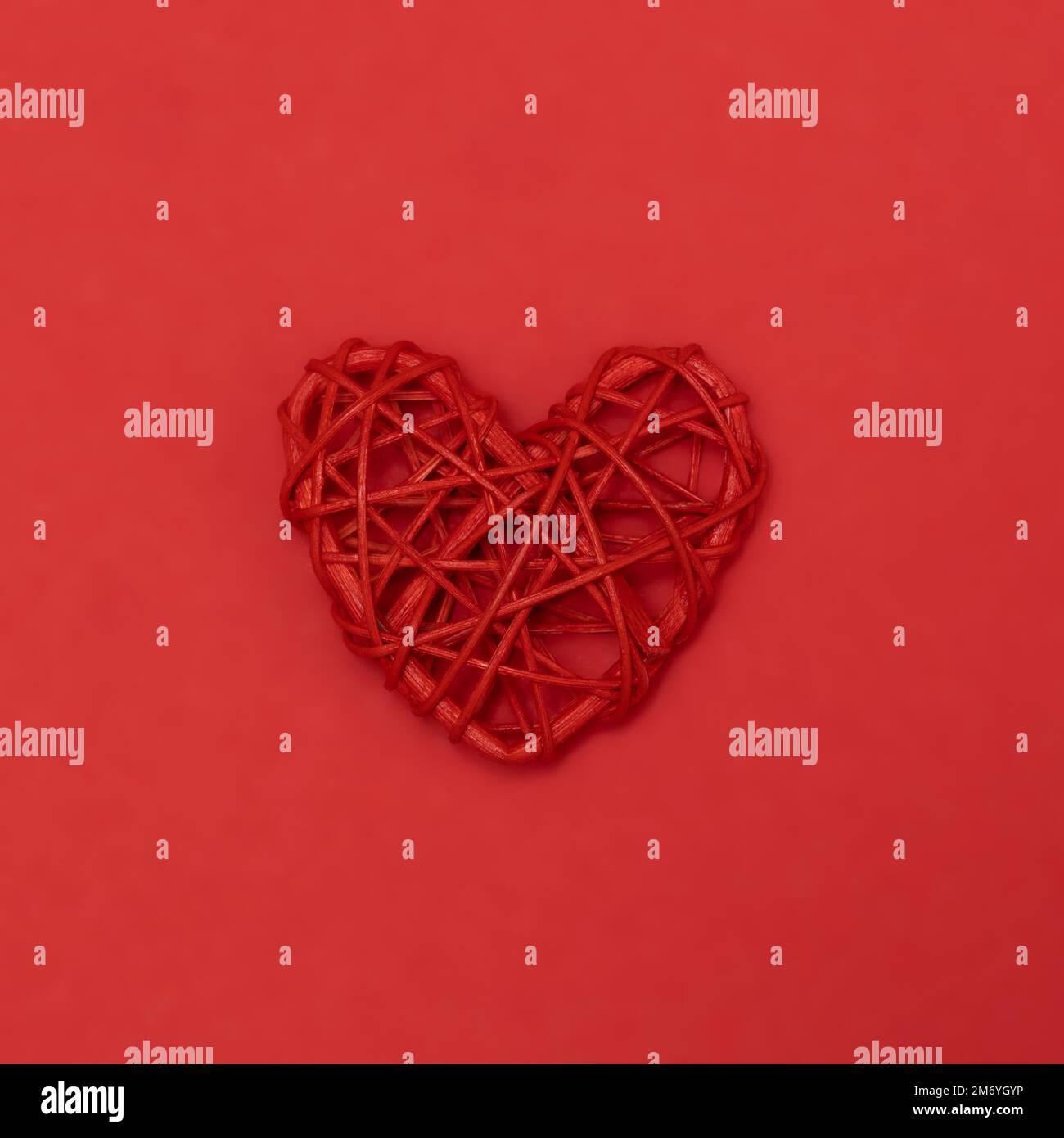 San Valentino rosso cuore rotang sullo stesso colore sfondo. Colori vivaci monocromatici. Eco San Valentino concetto di zero rifiuti giorno. Primo piano, copia spazio. Foto Stock