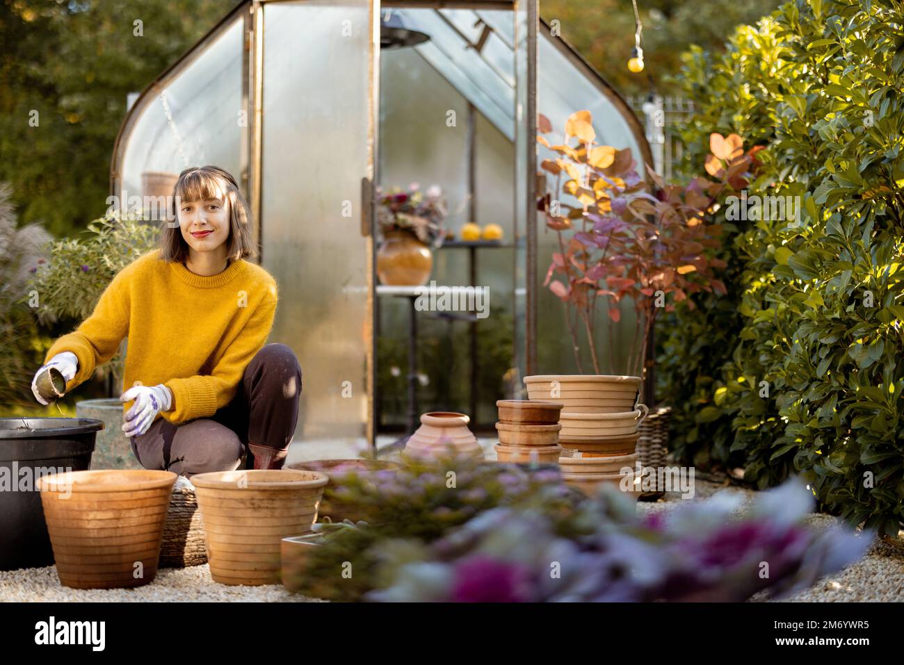 Donna che piantano fiori in brocche in giardino Foto Stock