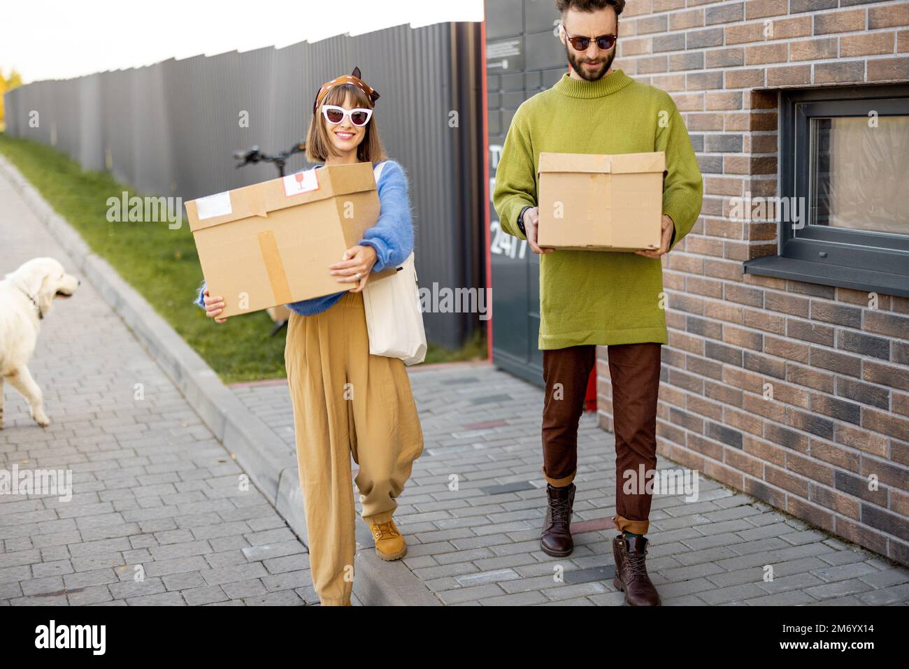 L'uomo e la donna trasportano pacchi ricevuti in macchina automatica posta all'aperto Foto Stock