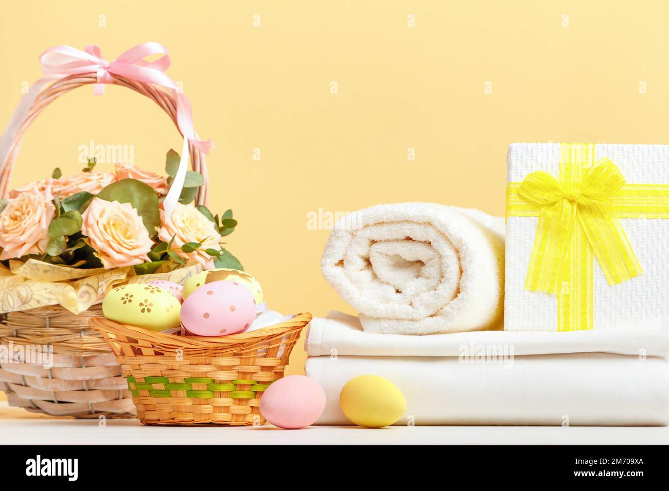 Pila di lenzuola bianche e rotoli di asciugamani con decorazioni pasquali sul tavolo Foto Stock