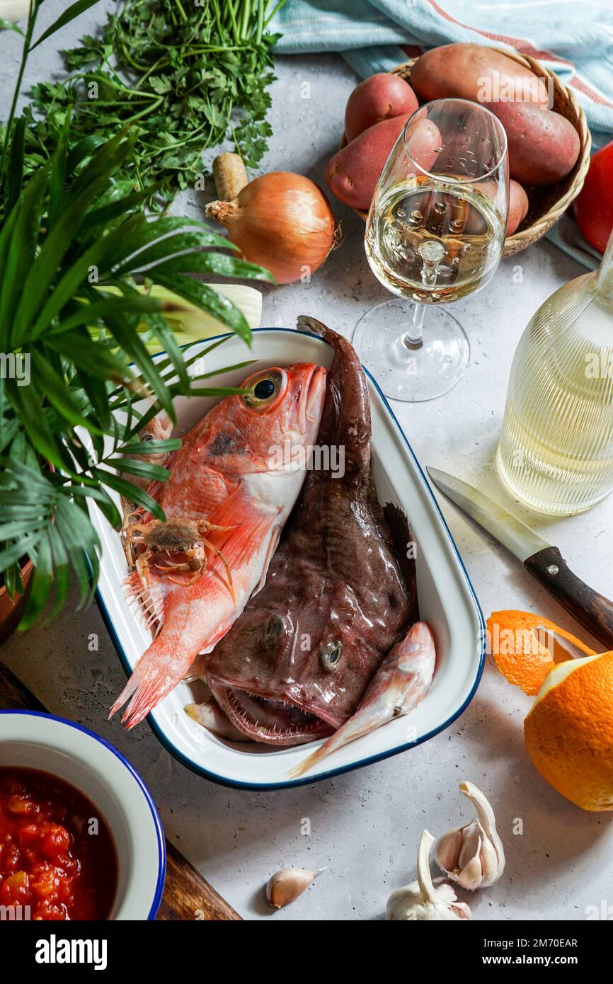 Ingredienti per la zuppa francese Bouillabaisse con pesce diavolo, Sebastes, con pomodori e vino bianco, vista dall'alto Foto Stock