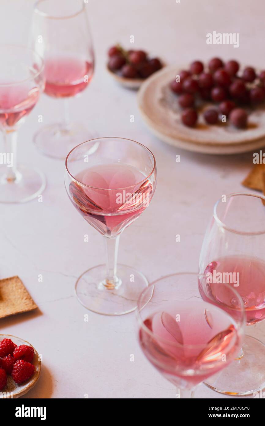 Bicchieri di vino rosa con uva sullo sfondo Foto Stock