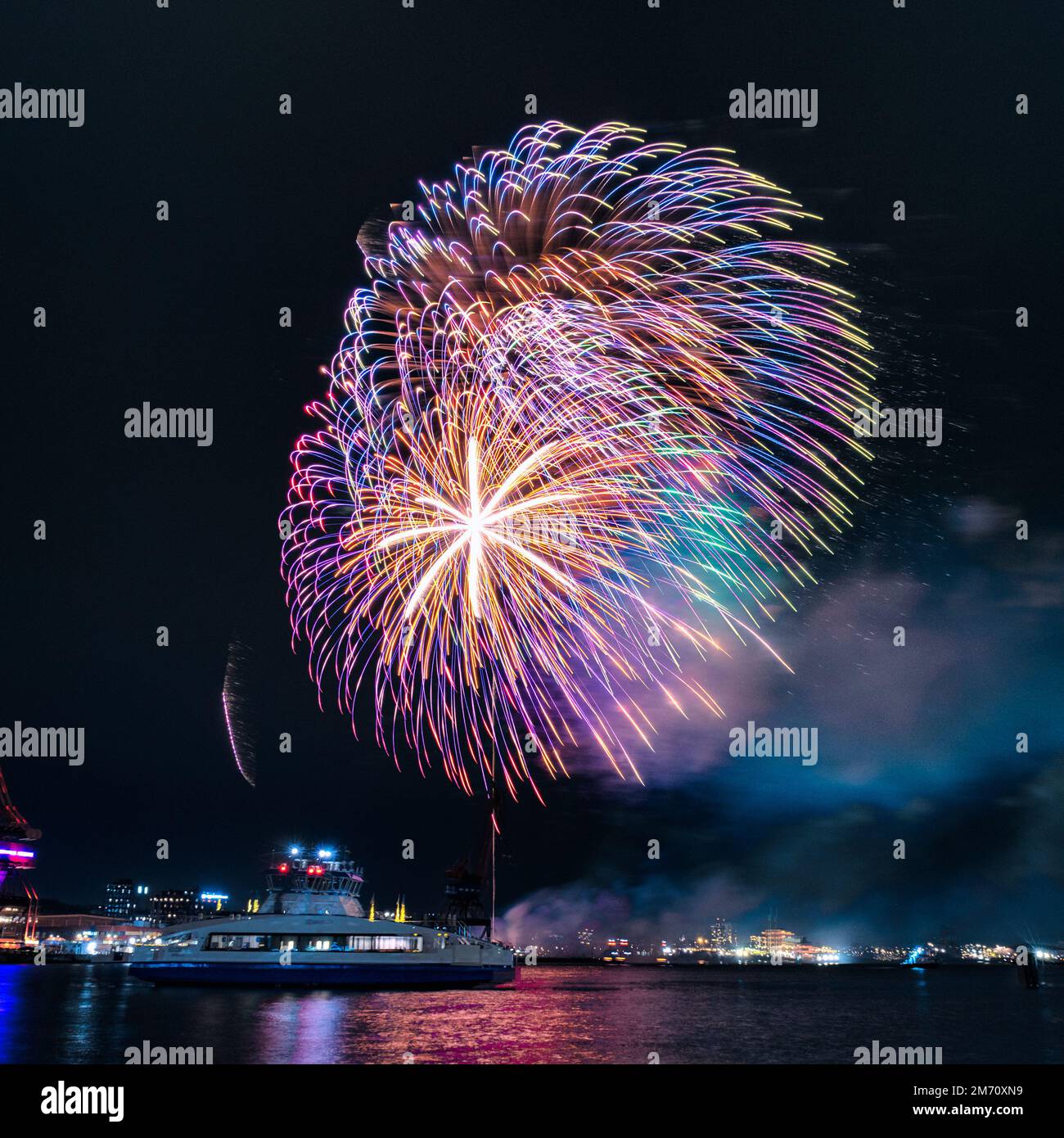 Fuochi d'artificio del nuovo anno a gothenburg svezia con vaporetto in primo piano e vecchie gru dai colori esplosivi Foto Stock