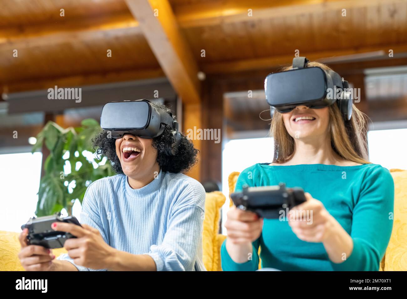 Due giovani donne giocano a videogame di realtà virtuale, persone che utilizzano cuffie e smartphone come la tecnologia di intrattenimento in contrazione, la realtà virtuale co Foto Stock