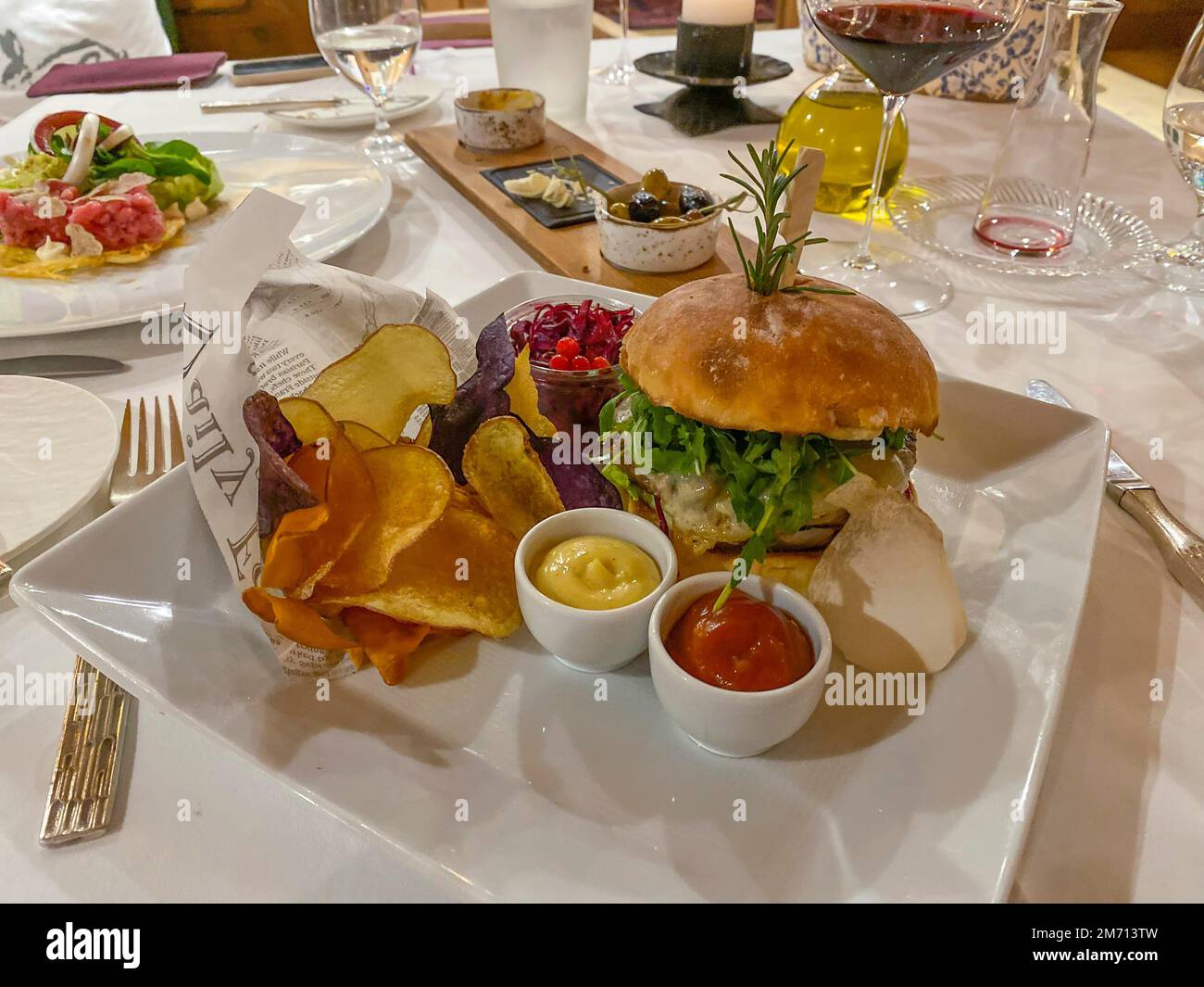 Portata principale, hamburger con cipolle, formaggio fuso, insalata di rucola, patatine, Senape e ketchup su un tavolo finemente decorato, Assia, Germania Foto Stock