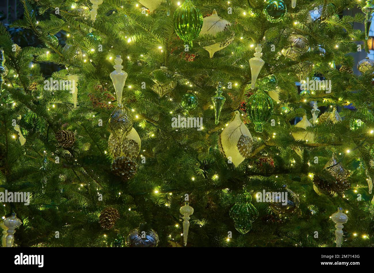 Grande albero di Natale, primo piano, luci gialle, ornamenti verdi, monocromatico, festivo, vacanza, inverno Foto Stock