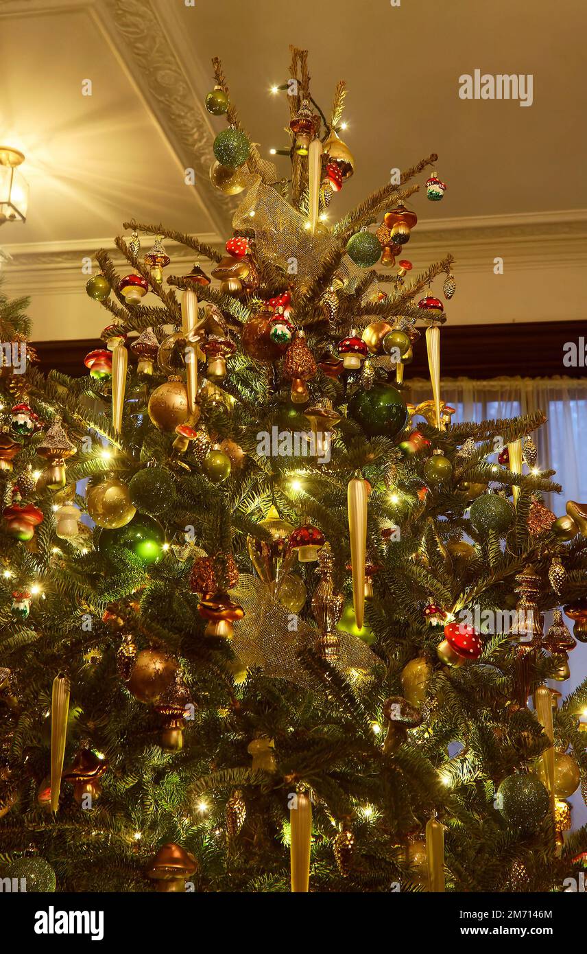 Grande albero di Natale, primo piano, luci gialle, ornamenti di funghi, ghiaccioli, palline d'oro, festive, vacanze, inverno Foto Stock