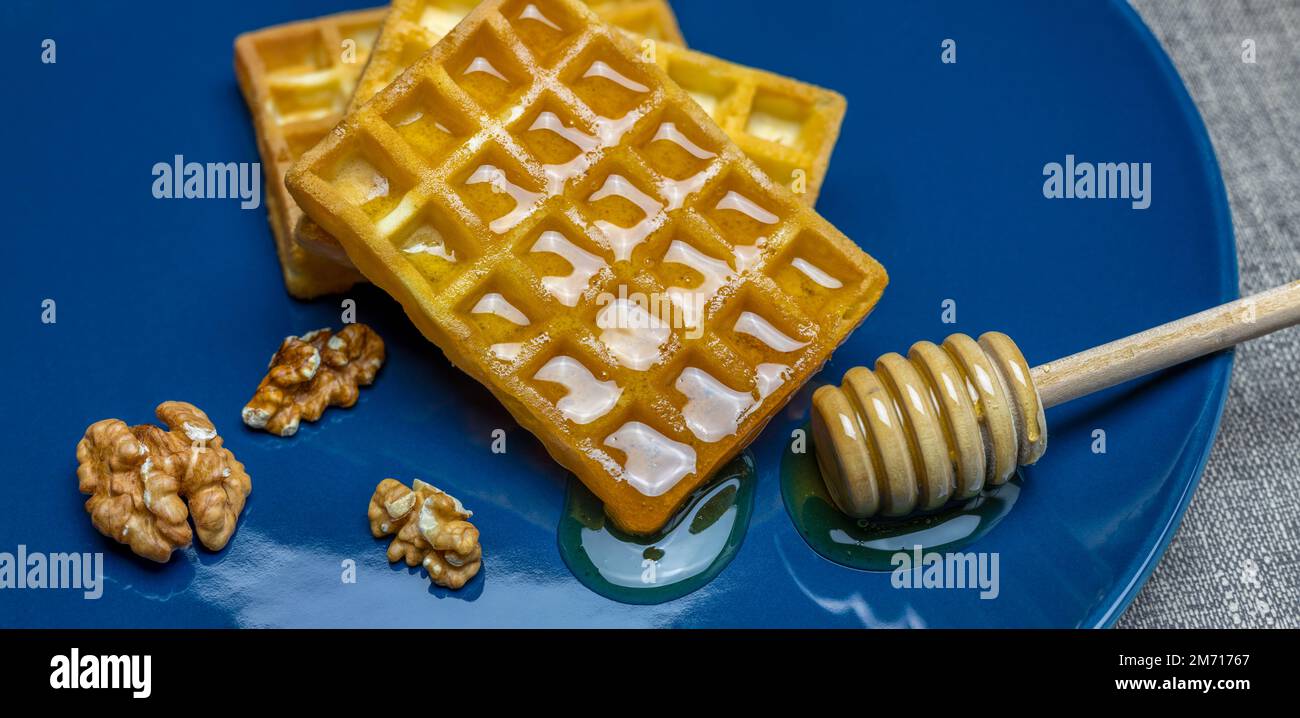 striscione o waffle con sciroppo d'acero e noci su piatto blu Foto Stock