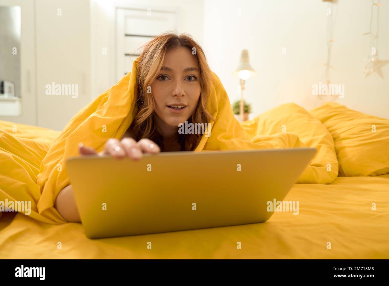 Giovane donna con computer portatile in una camera da letto ben illuminata Foto Stock