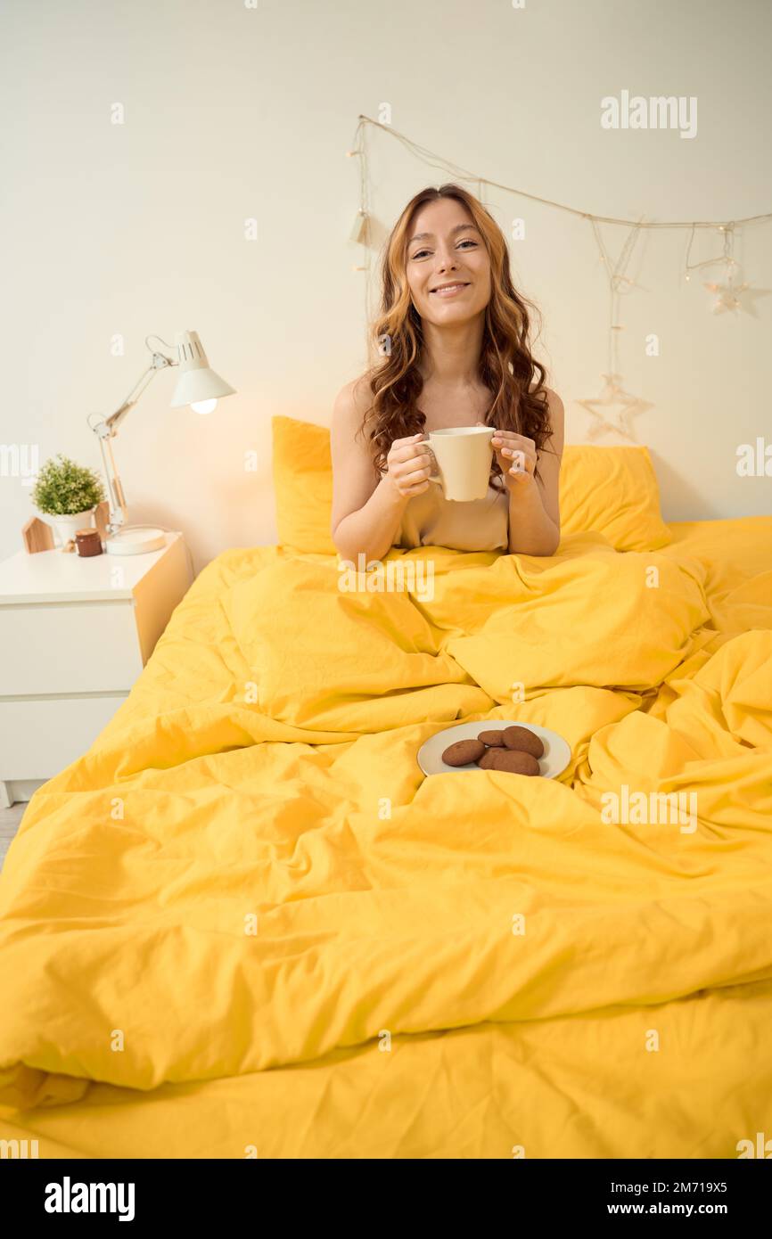 Ragazza allegra godendo il suo pasto mattutino in camera da letto Foto Stock