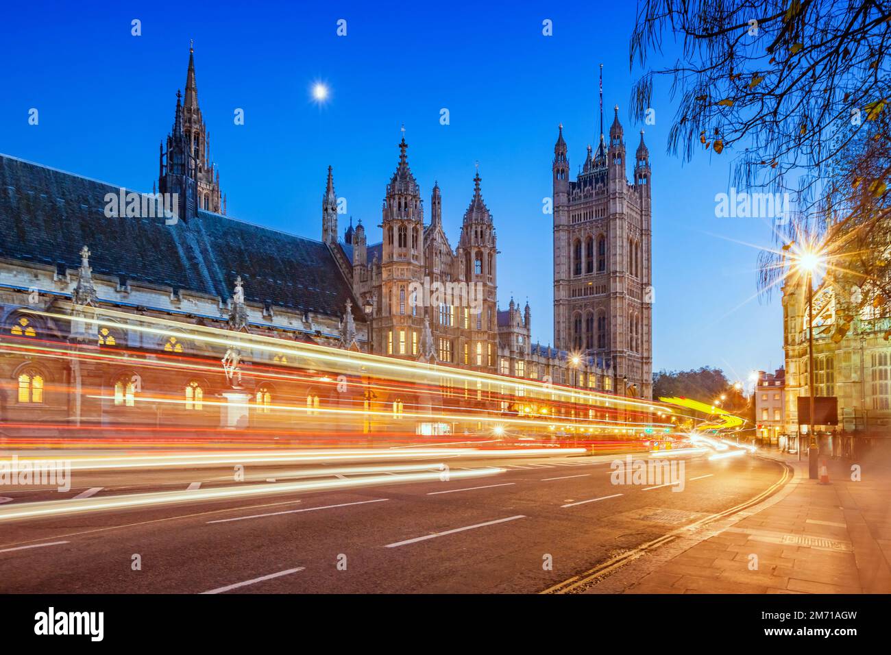 Le auto passano accanto al Westminster Palace a Londra, Inghilterra, Regno Unito al crepuscolo Foto Stock