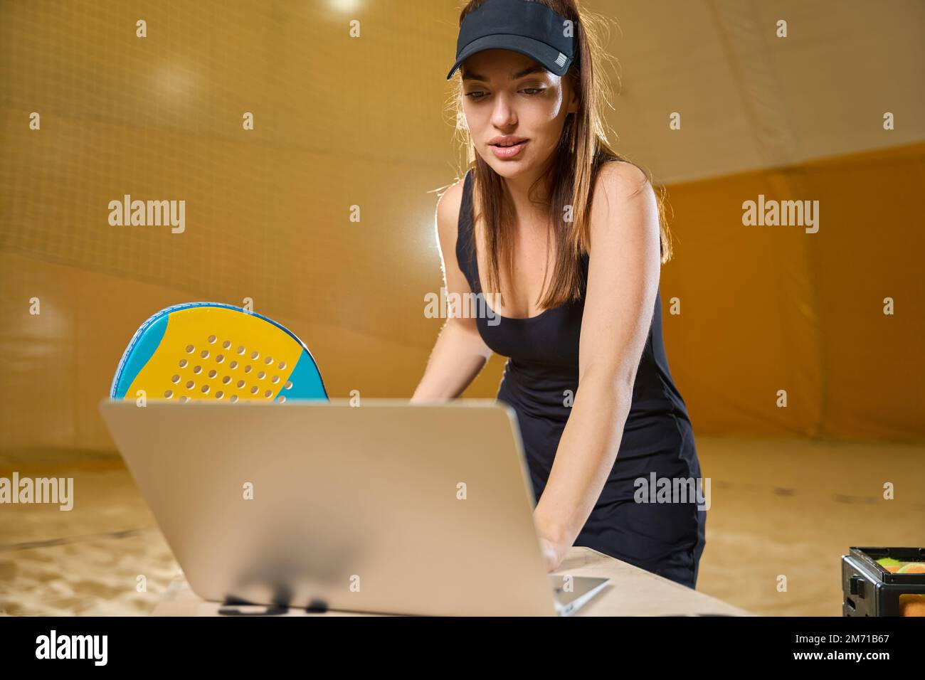 Donna che si prepara per il gioco di tennis in spiaggia al coperto e utilizzando gadget Foto Stock