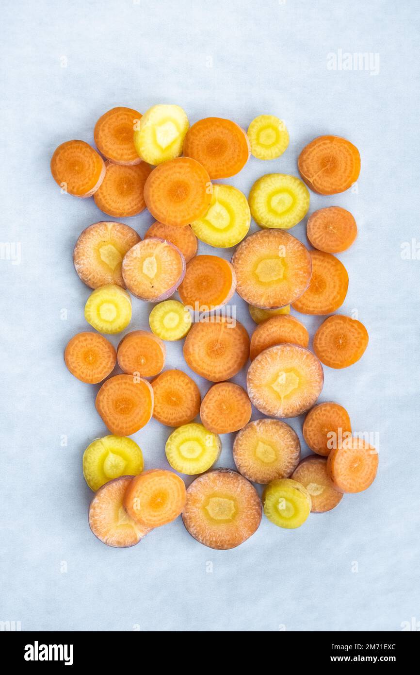 Un primo piano di carote gialle e arancioni tagliate, visualizzate in alto con un motivo geometrico. Foto Stock