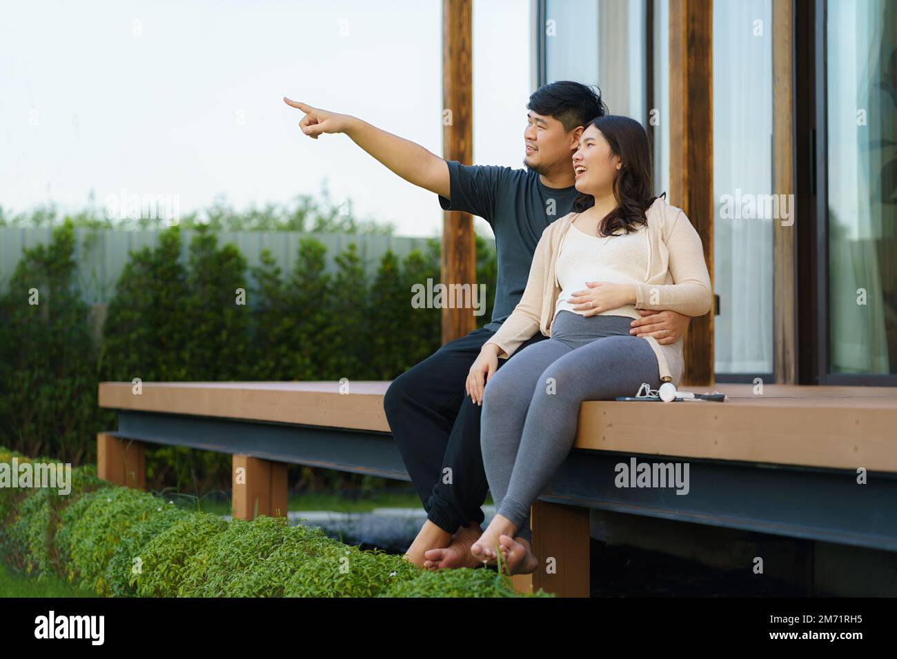 Donna asiatica incinta con suo marito che parla insieme in terrazza a casa per rilassarsi e respirare aria fresca. Foto Stock