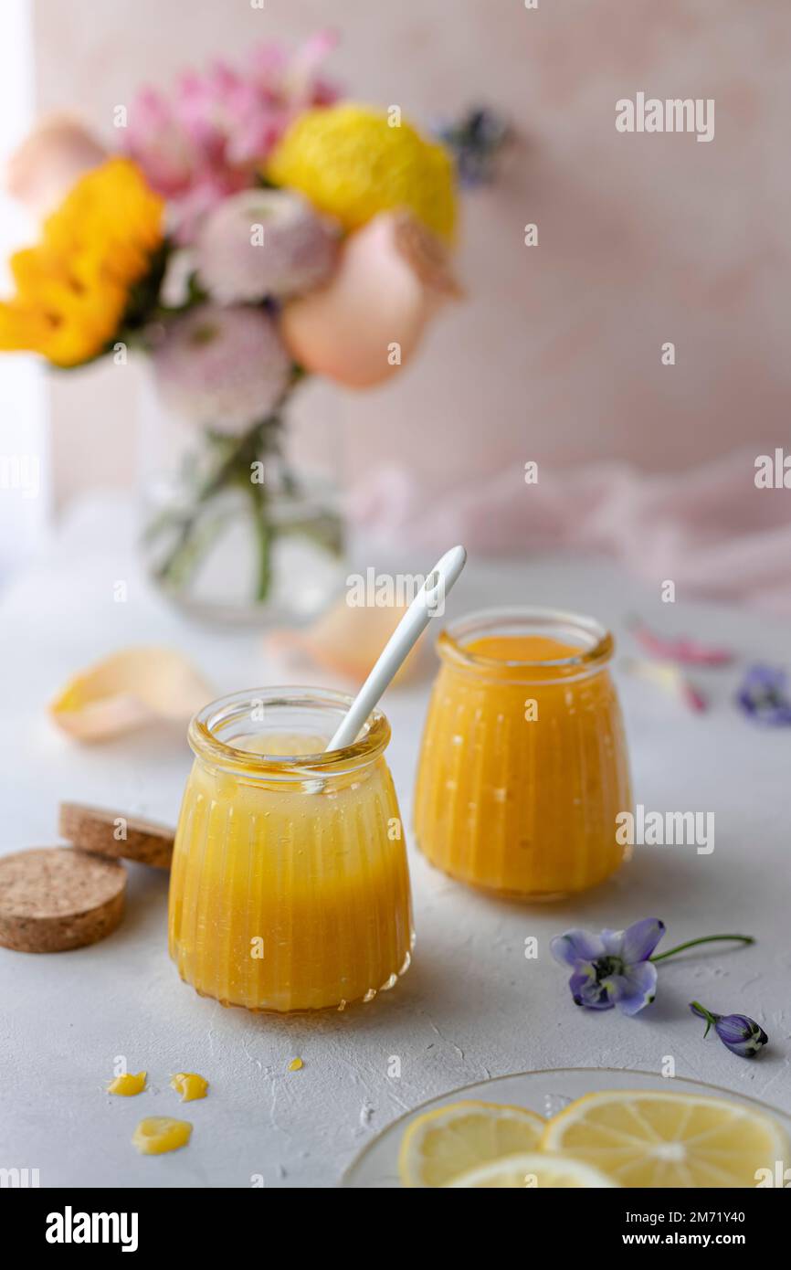 Cagliata di limone in vasetti di vetro decorati con fiori primaverili e pastelli Foto Stock