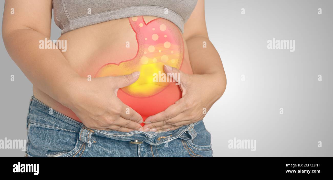 Reflusso acido o bruciore di cuore, lo stomaco è sullo sfondo grigio del corpo della donna, concetto di anatomia Foto Stock