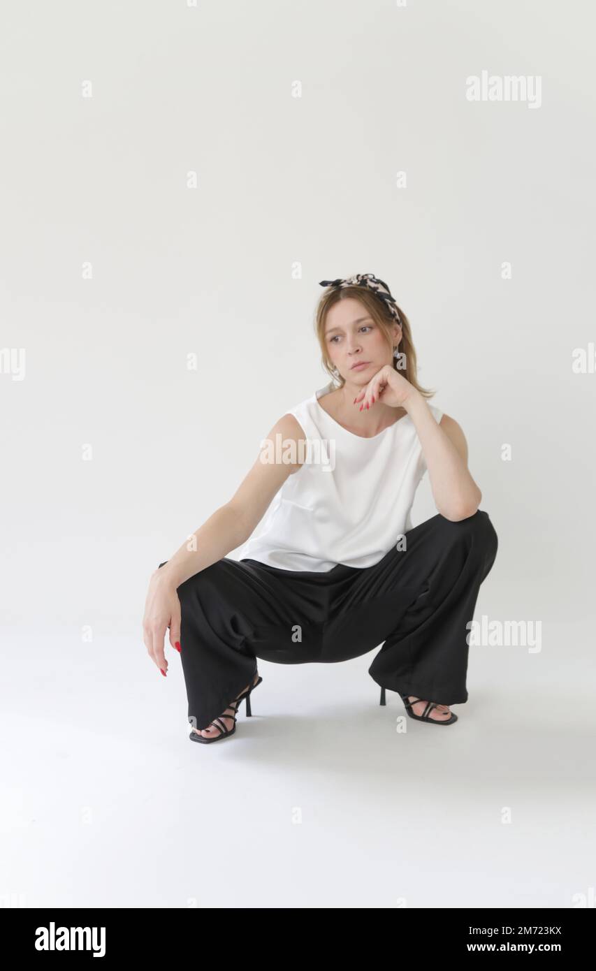 Serie di foto di studio di giovane modella femminile in abito in seta bianco e nero, blusa senza maniche e pantaloni a gambe larghe Foto Stock