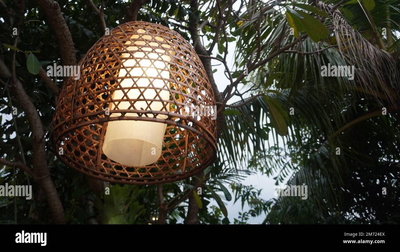 Lampada di lampione da coperta tessuta di bambù appesa nell'albero Foto Stock