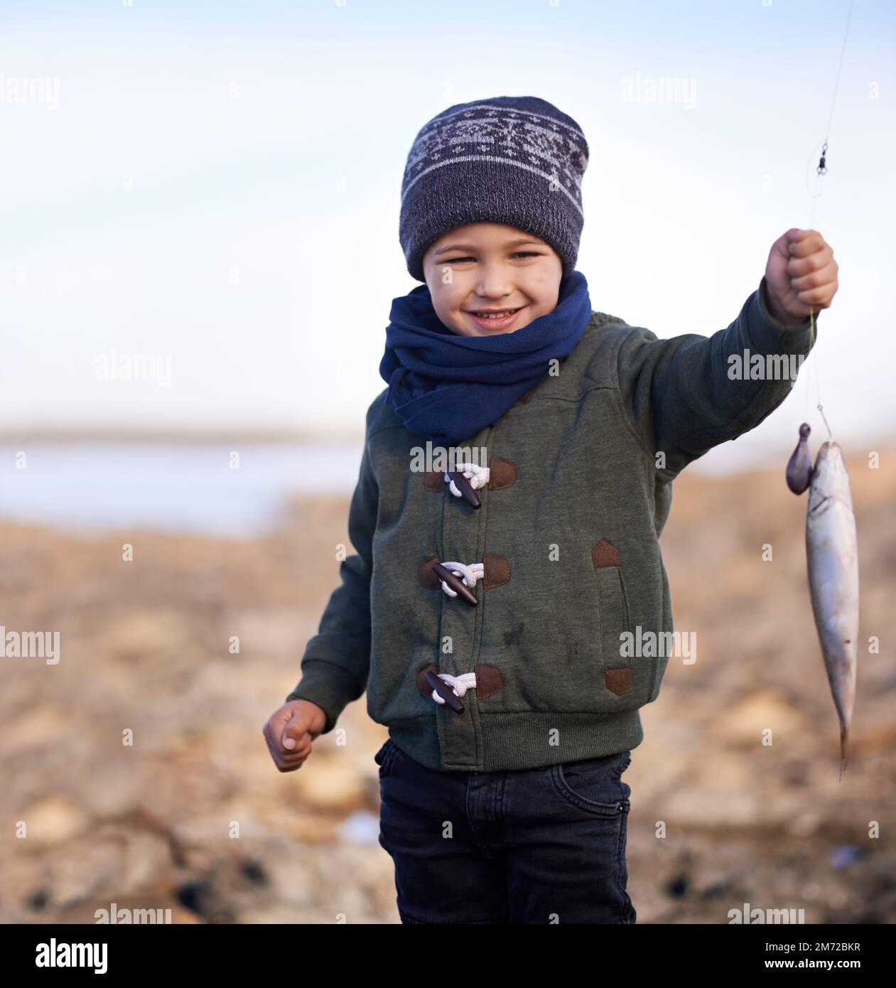 Guardate questo piccolo ragazzo. un ragazzino carino che tiene il pesce che ha pescato. Foto Stock