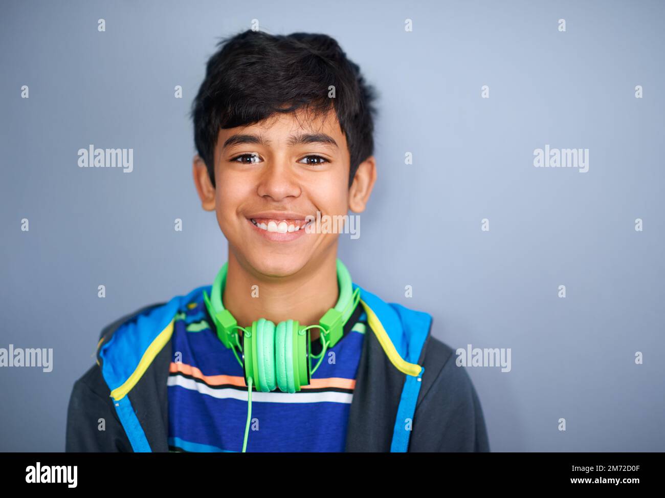 Produttore di musica del futuro. Un ragazzo giovane e carino, in piedi e sorridente su uno sfondo grigio. Foto Stock