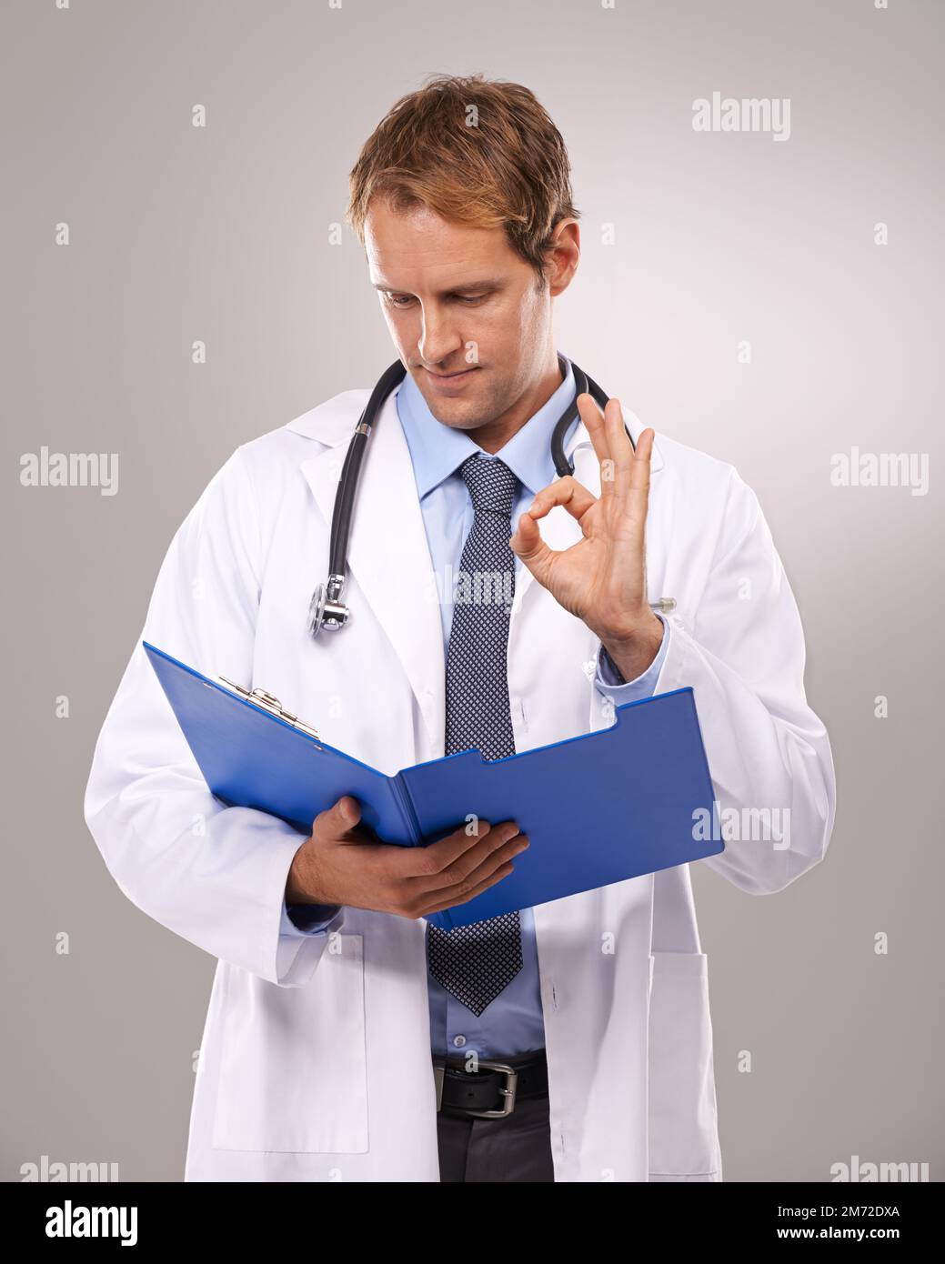 Stai andando a-ok. un medico che tiene la lettura di una cartella pazienti e che mostra il segno ok. Foto Stock