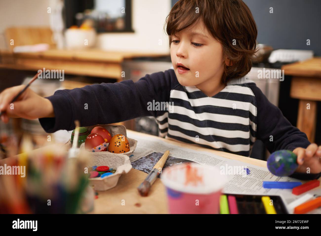 Il coniglietto li amerà. un ragazzino che arriva a dipingere mentre dipinge le uova di pasqua. Foto Stock